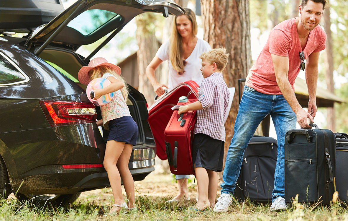 family dressed for summer packing car with suitcases for a holiday